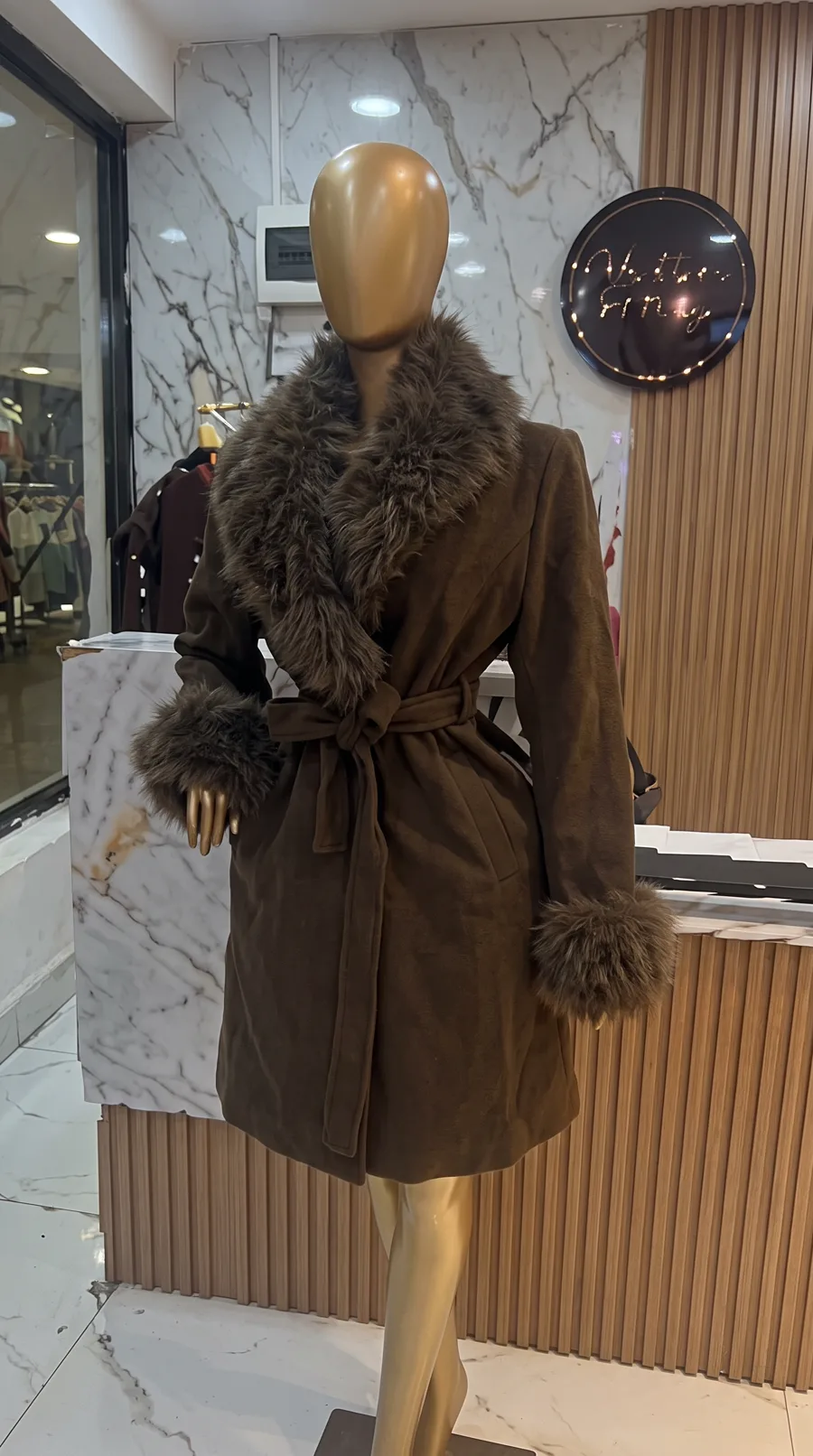 A brown belted coat with a faux-fur collar and cuffs on a shop mannequin