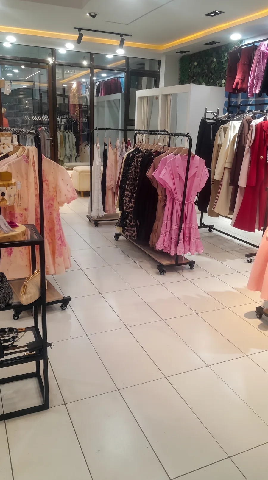 An empty boutique floor: rails of dresses and coats under warm ceiling lights